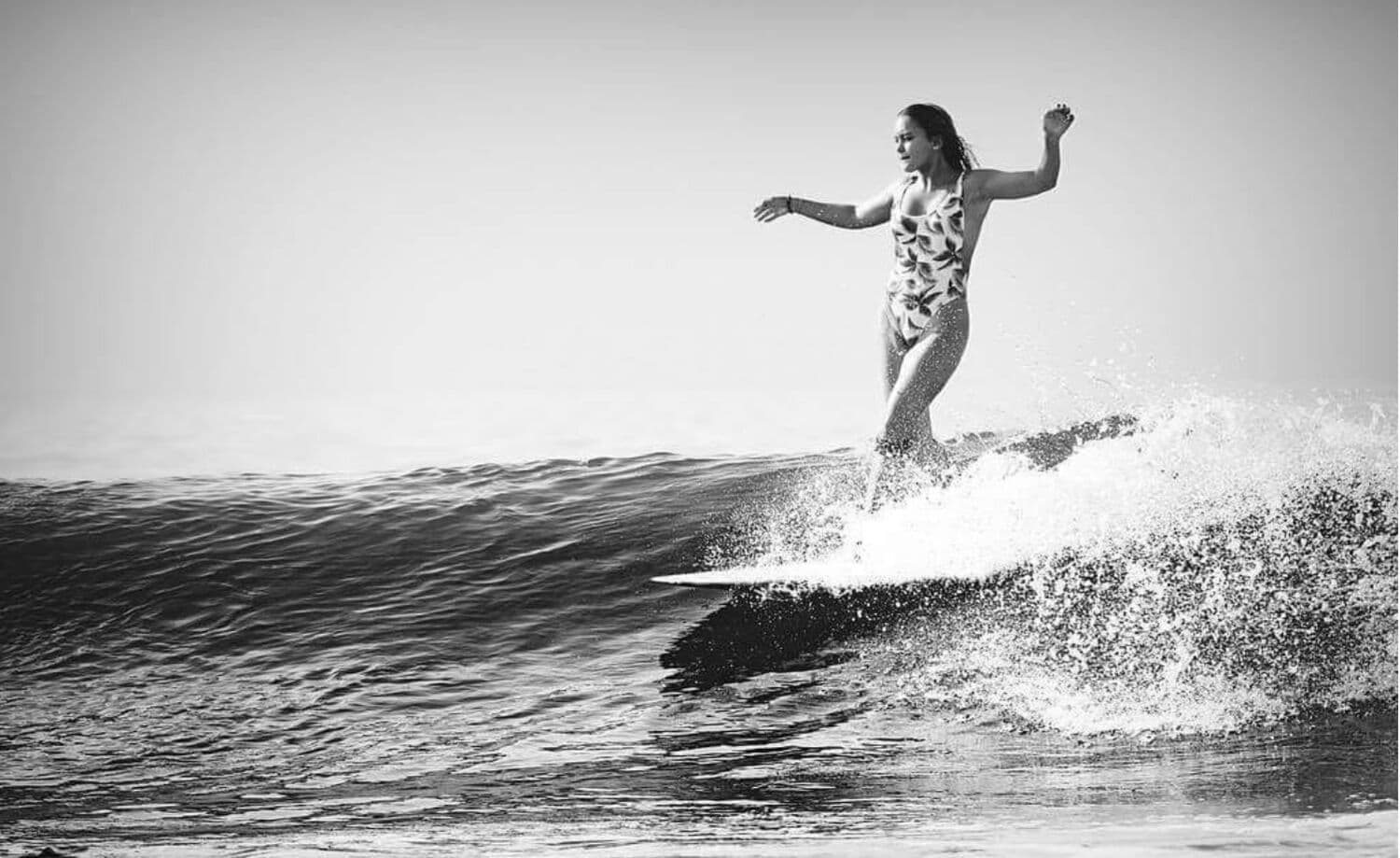 A black-and-white shot of a surfer trimming a longboard