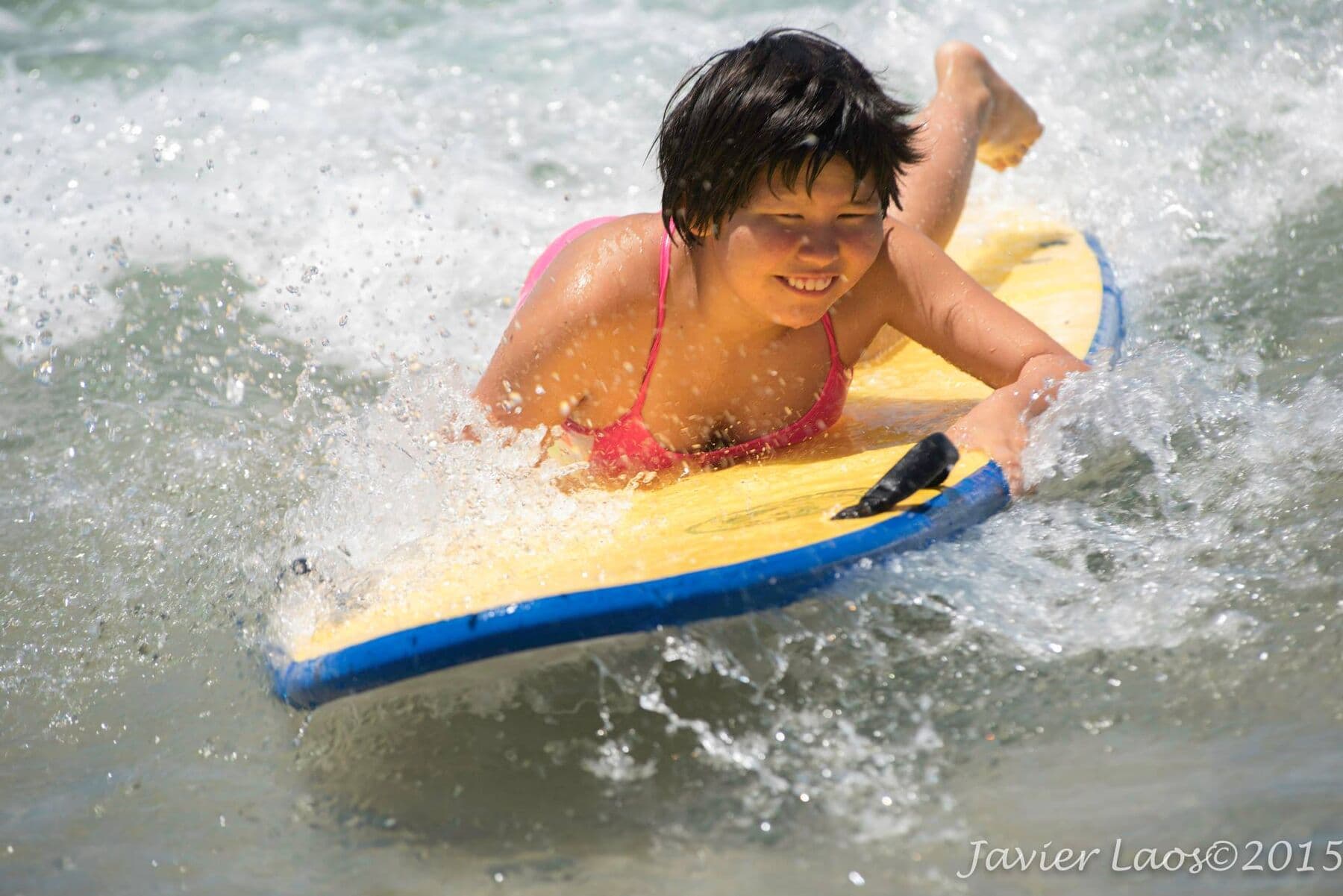 A smiling kid riding a bodyboard at Day at the Beach