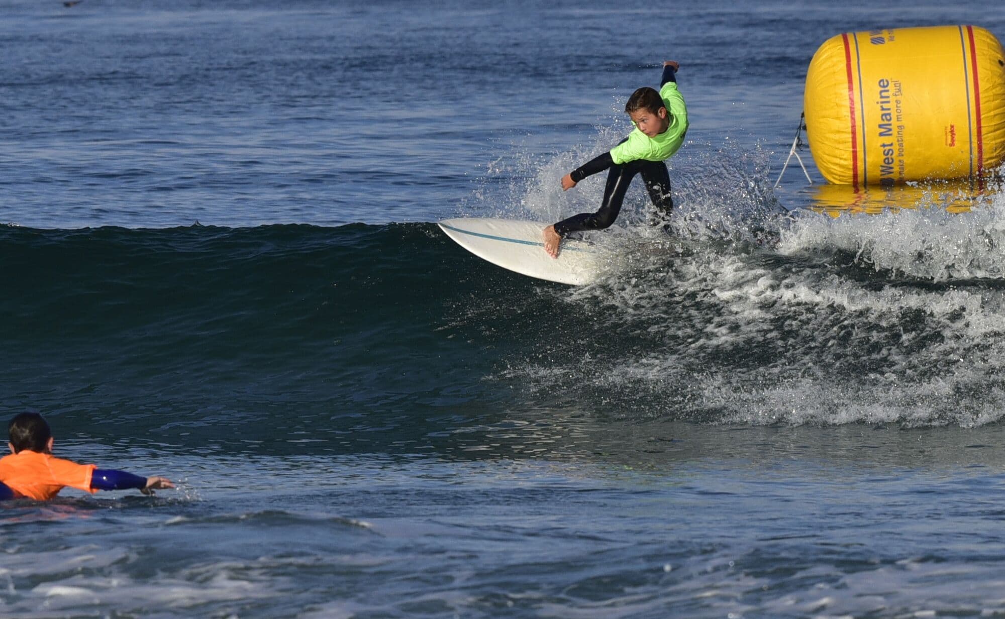 A grom surfing past the contest buoy at the Menehune