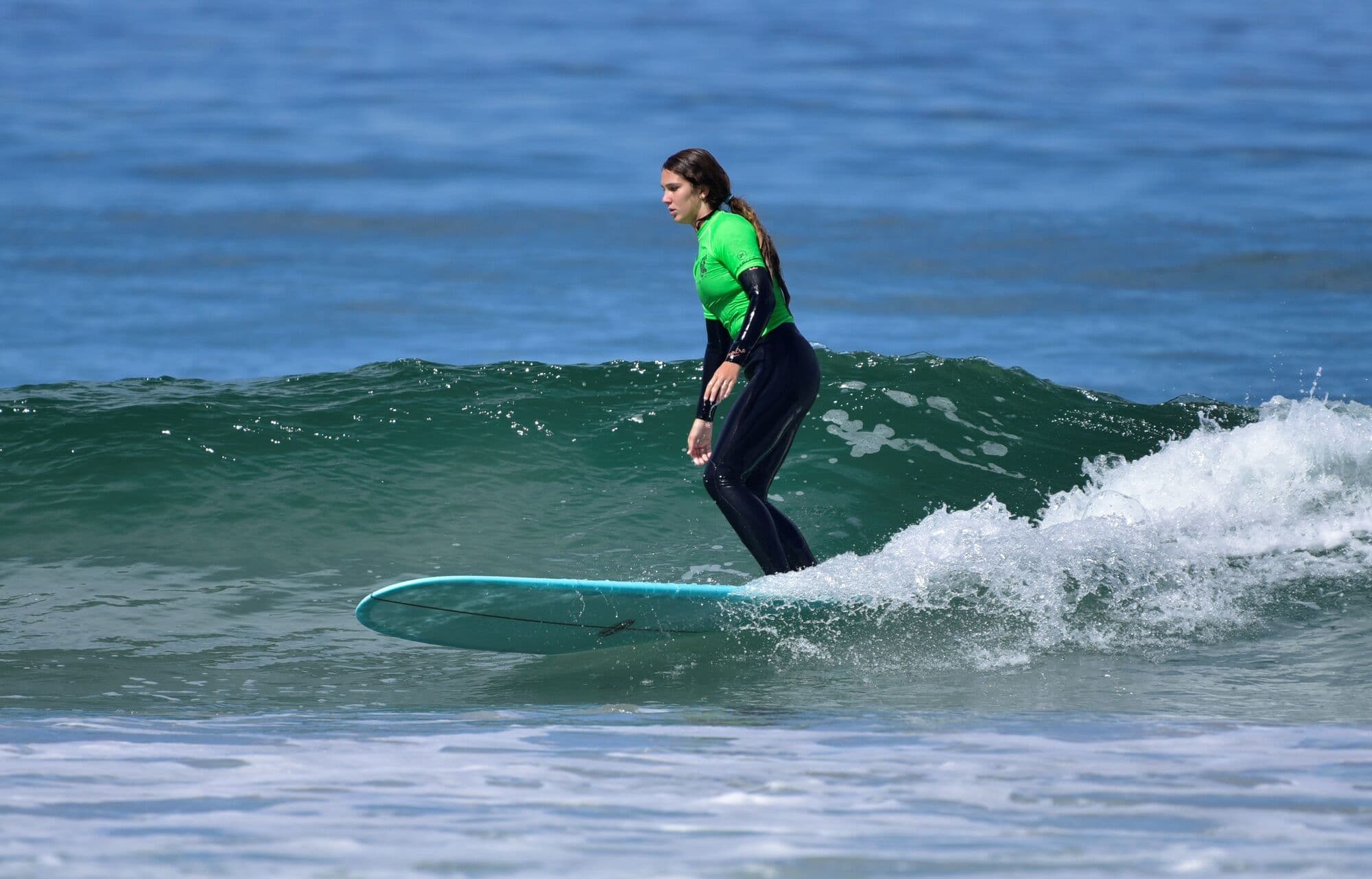 A junior surfer gliding along a green wall